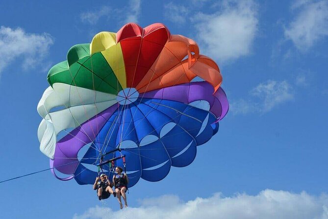 A striped parasail canopy under tow above open water